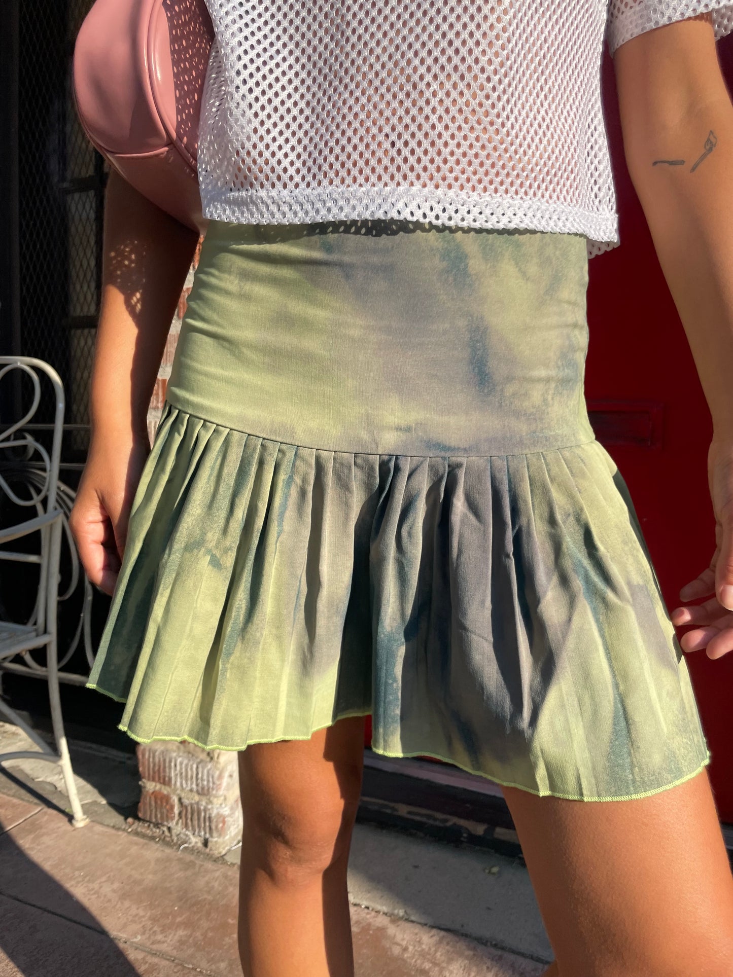Green pleated skirt held by a person against a blurred background