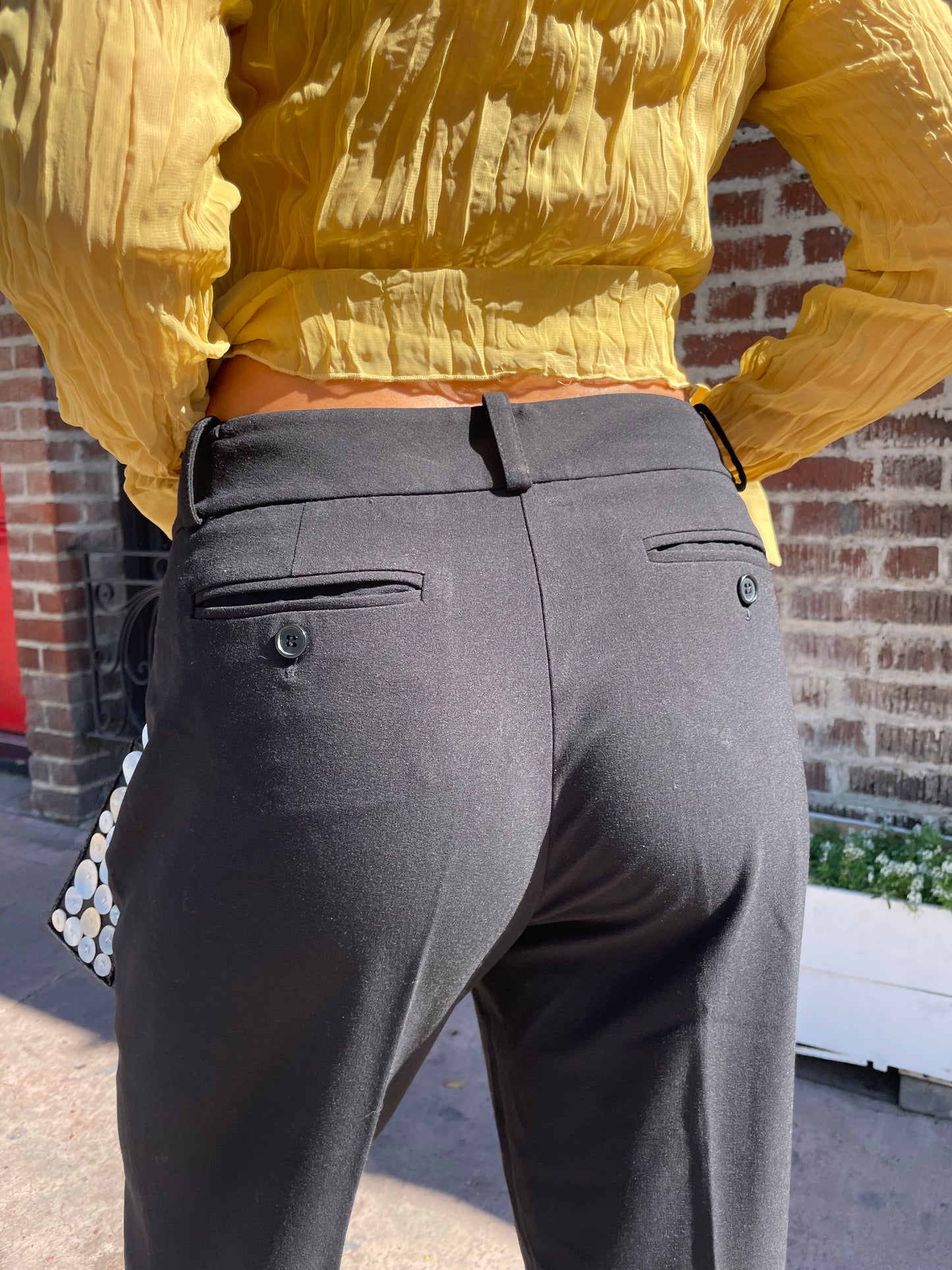 back of girl wearing gold top and black trousers