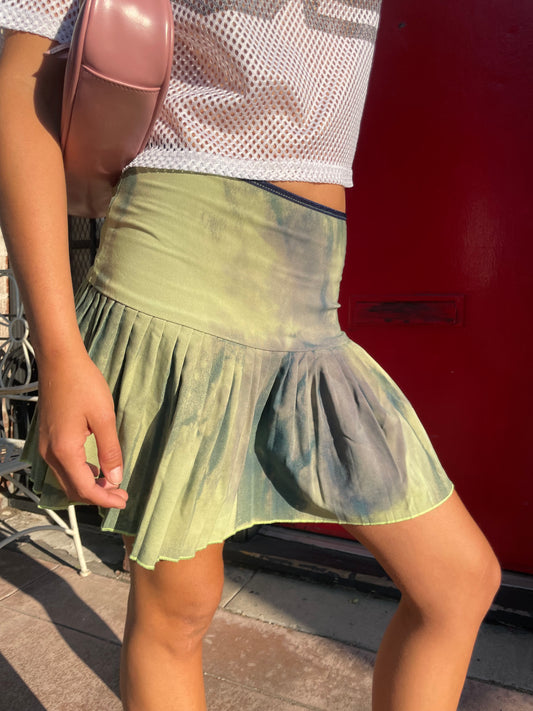 Person wearing a green dress with a red vehicle in the background