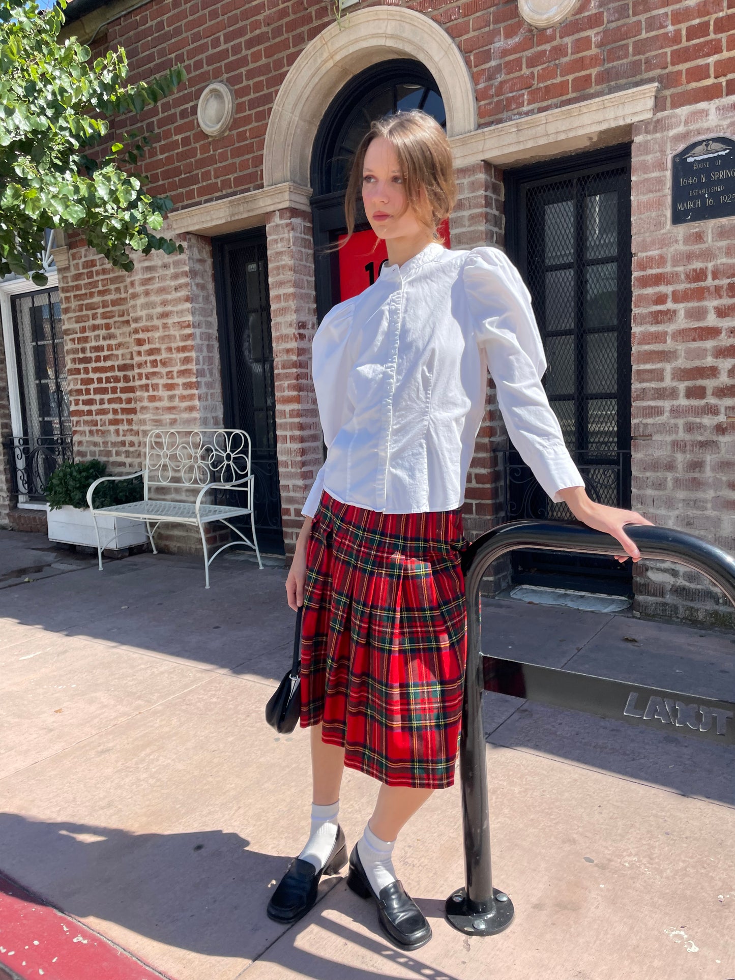 girl in white button up and plaid red skirt