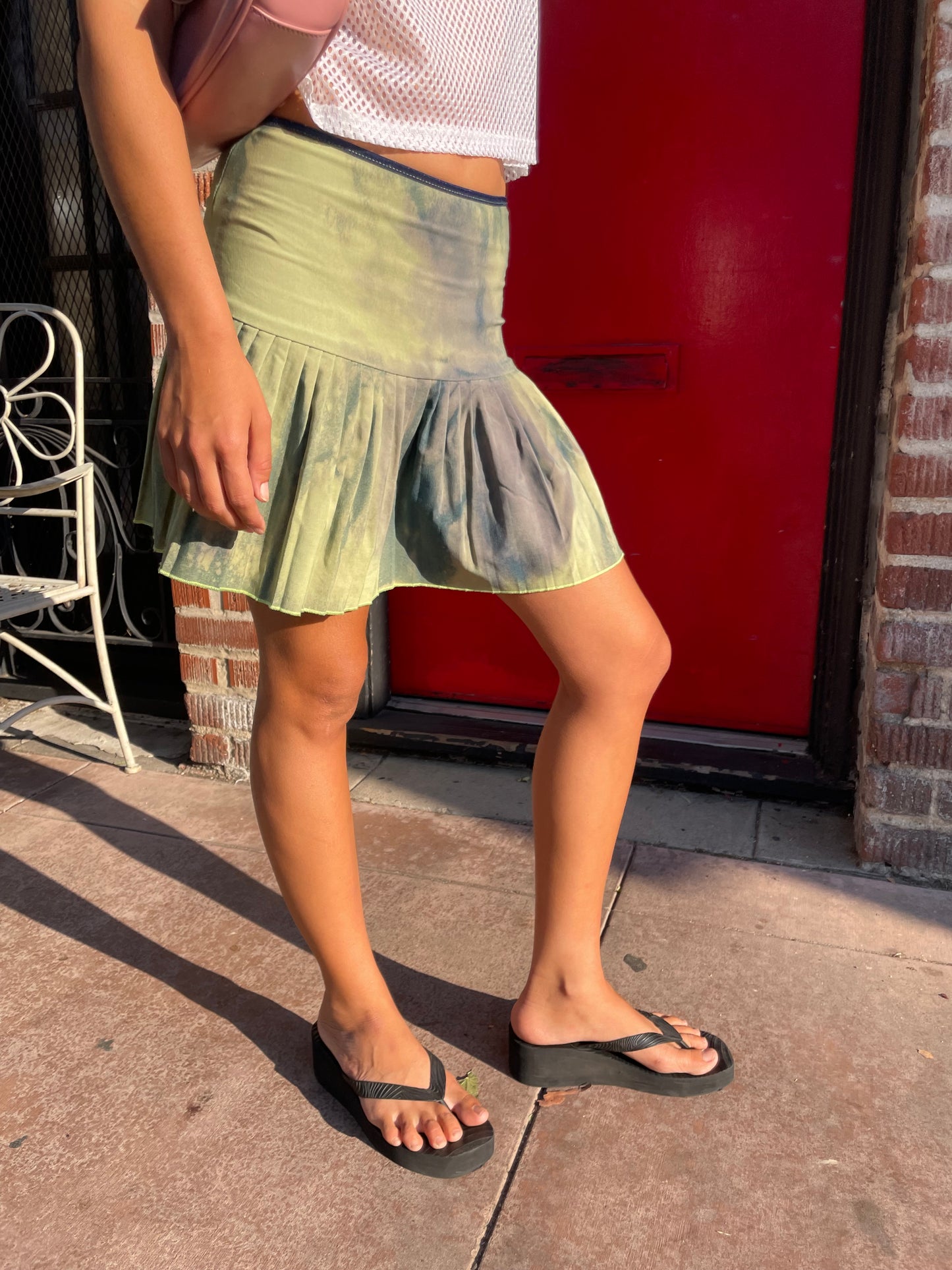 Person wearing a green dress and black sandals standing on a red vehicle.