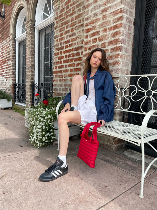girl wearing blue jacket with red stripe, white tank top and white skirt