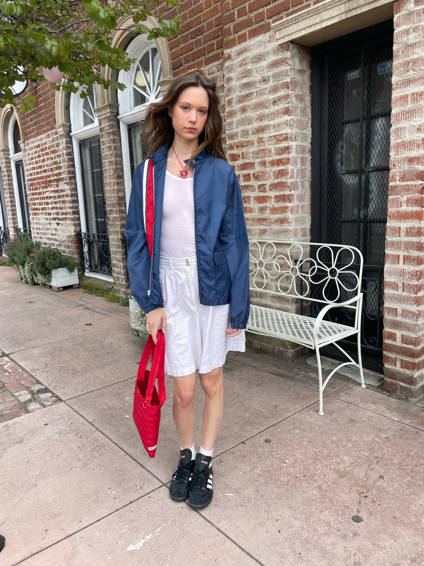 girl wearing blue jacket with red stripe, white tank top and white skirt