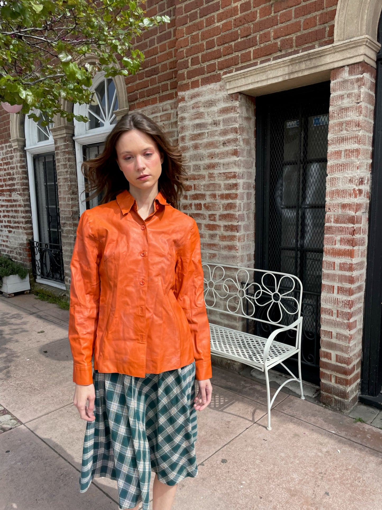 girl wearing orange jacket and green plaid skirt