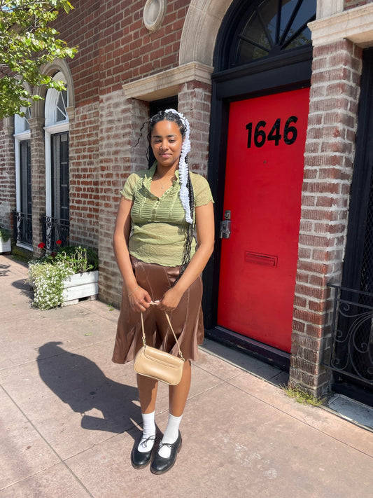 front of girl wearing green top and pink silk skirt