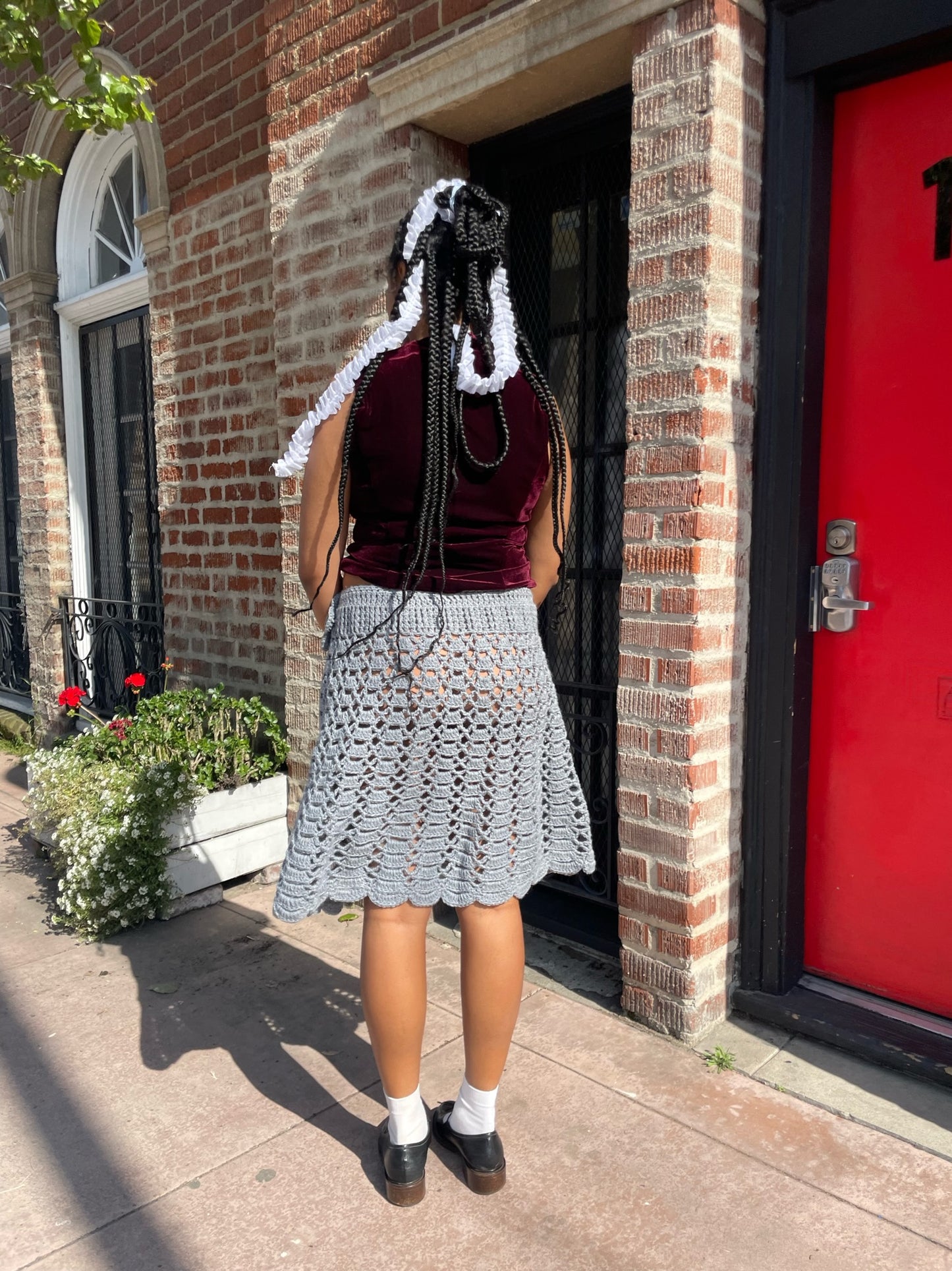 girl wearing a red velvet vest and light blue crochet skirt