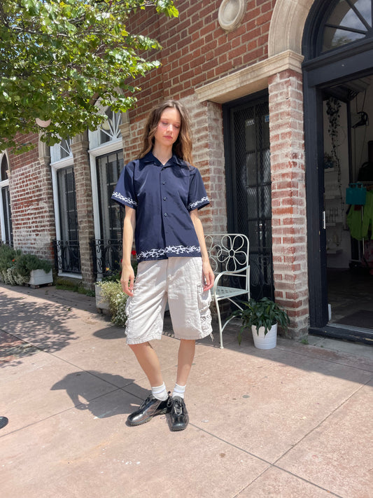 girl wearing a button up blue shirt and white cargo shorts.