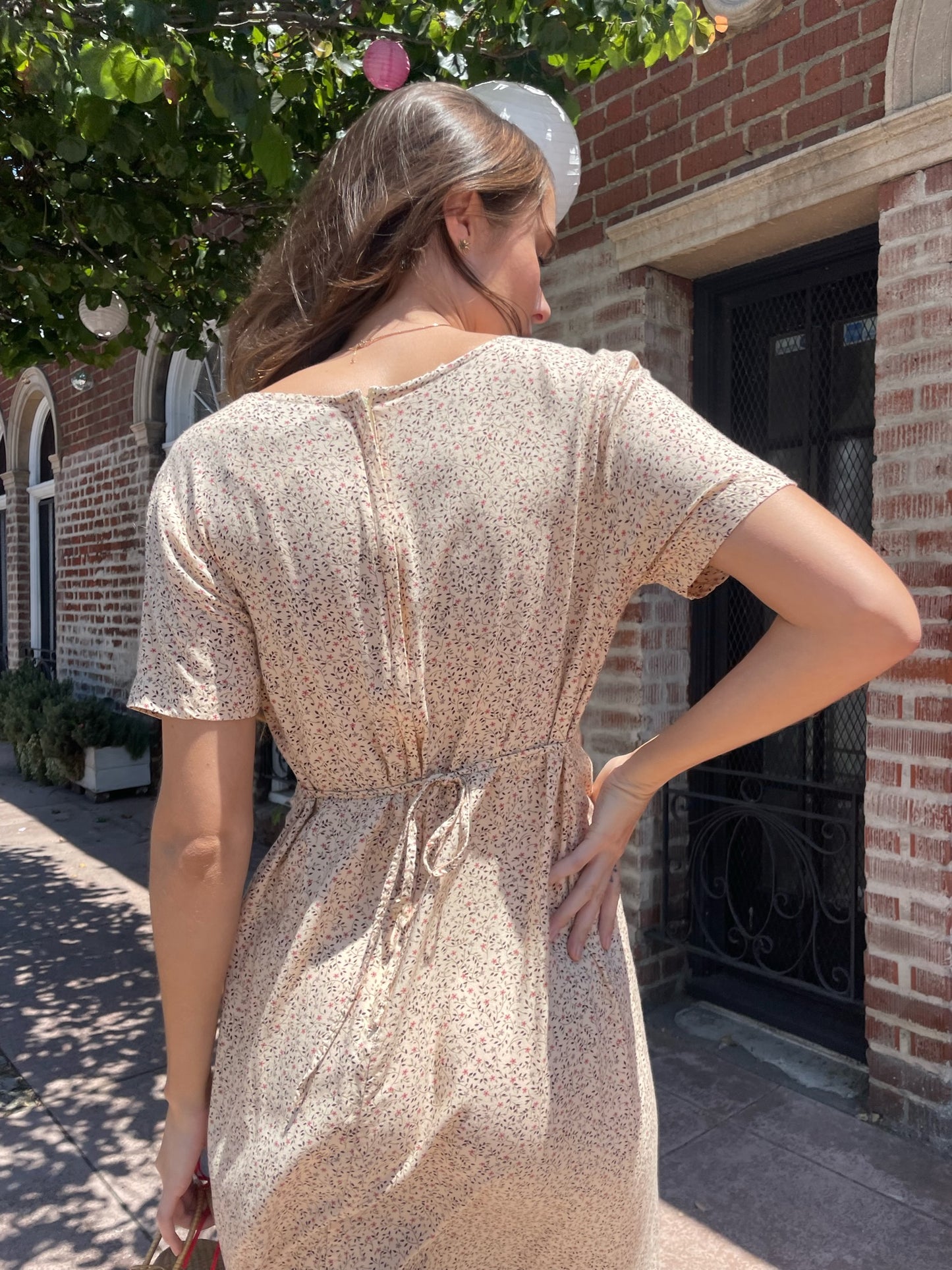 girl wearing cream floral dress, wicker handbag, and black leather boots
