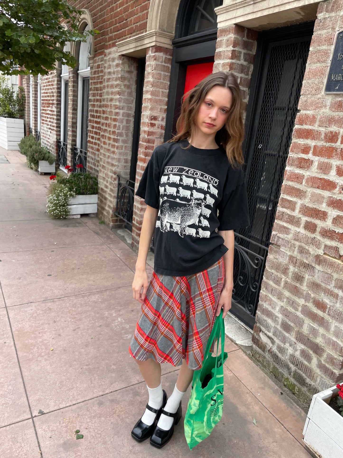 girl wearing graphic t-shirt and plaid skirt