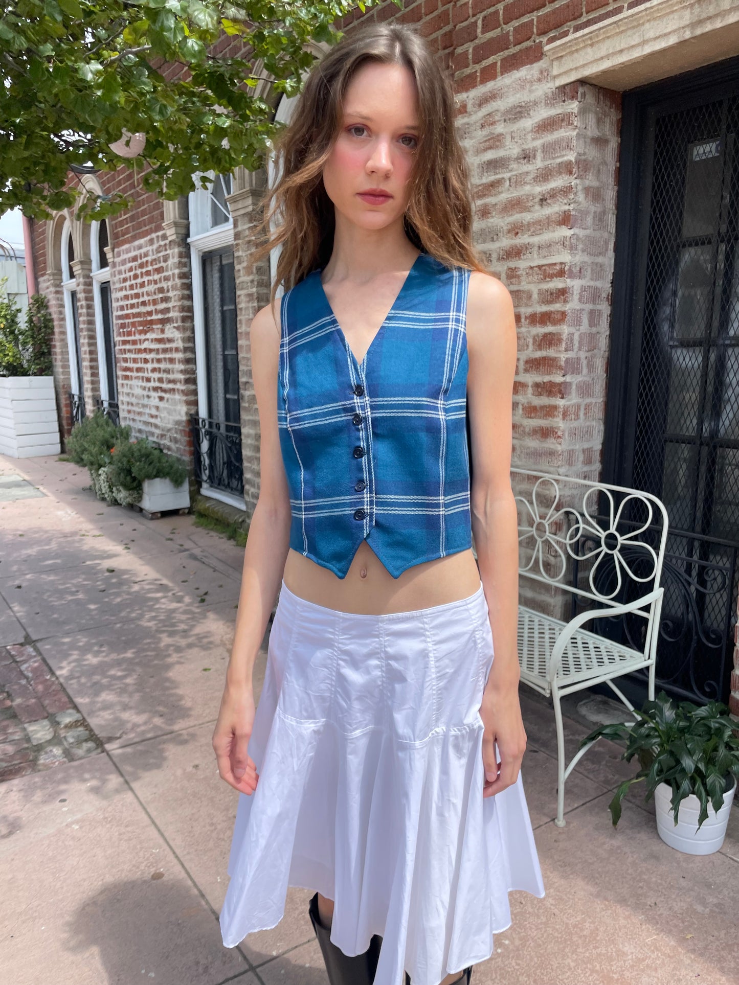 girl wearing blue plaid vest, white skirt and black boots