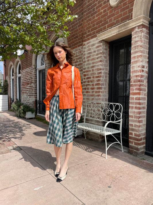 girl wearing green plaid knee length skirt and orange top
