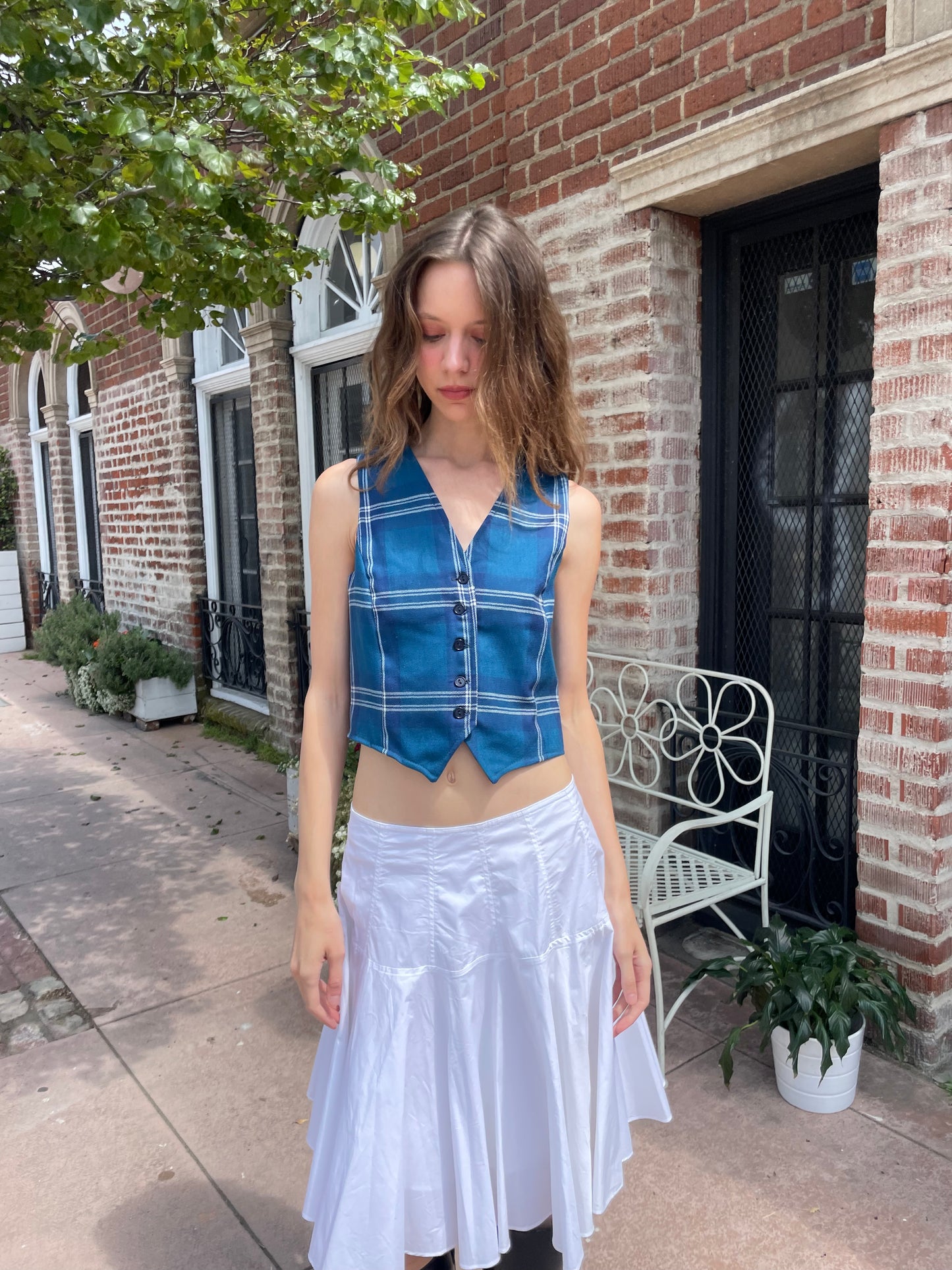 girl wearing blue plaid vest, white skirt and black boots