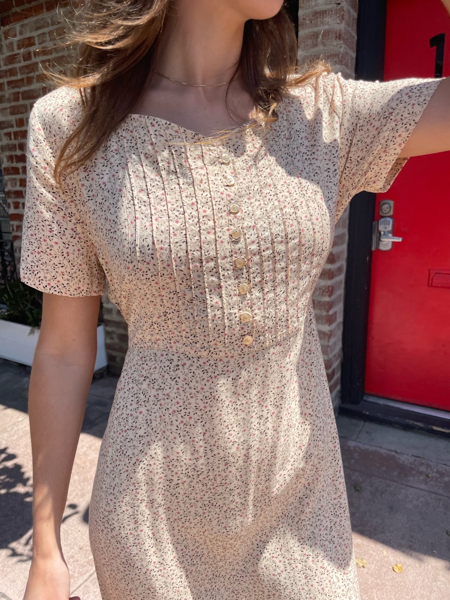 girl wearing cream floral dress, wicker handbag, and black leather boots