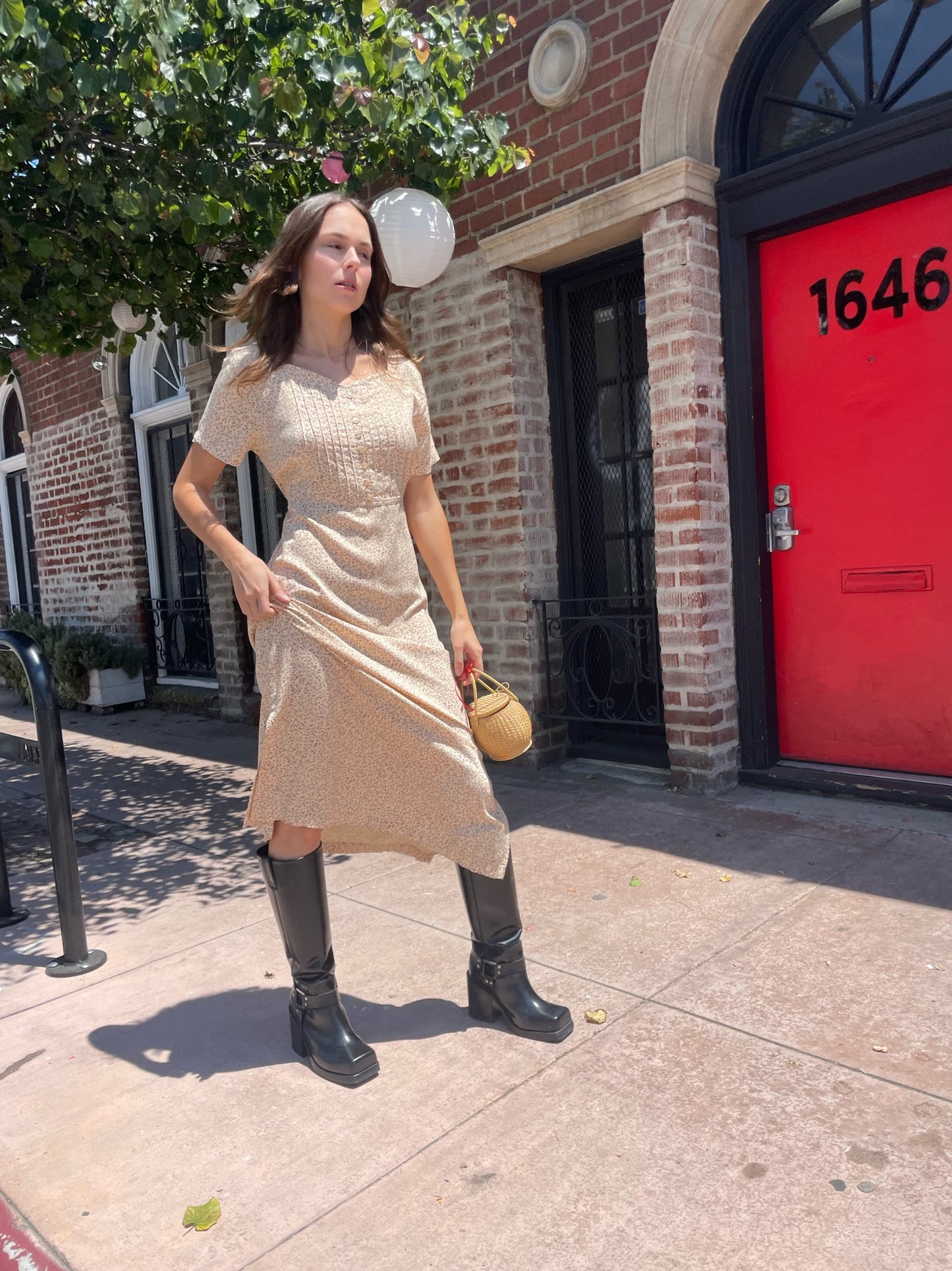 girl wearing cream floral dress, wicker handbag, and black leather boots