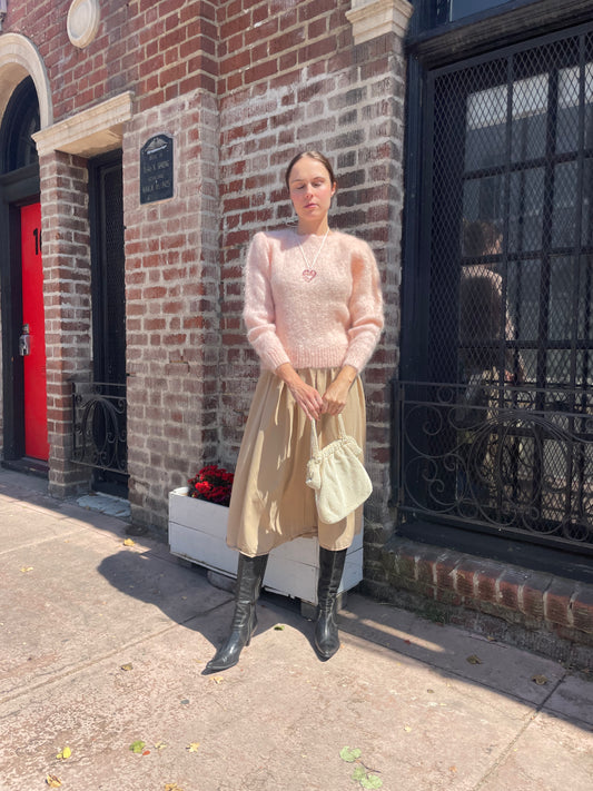 girl in tan skirt and light pink sweater