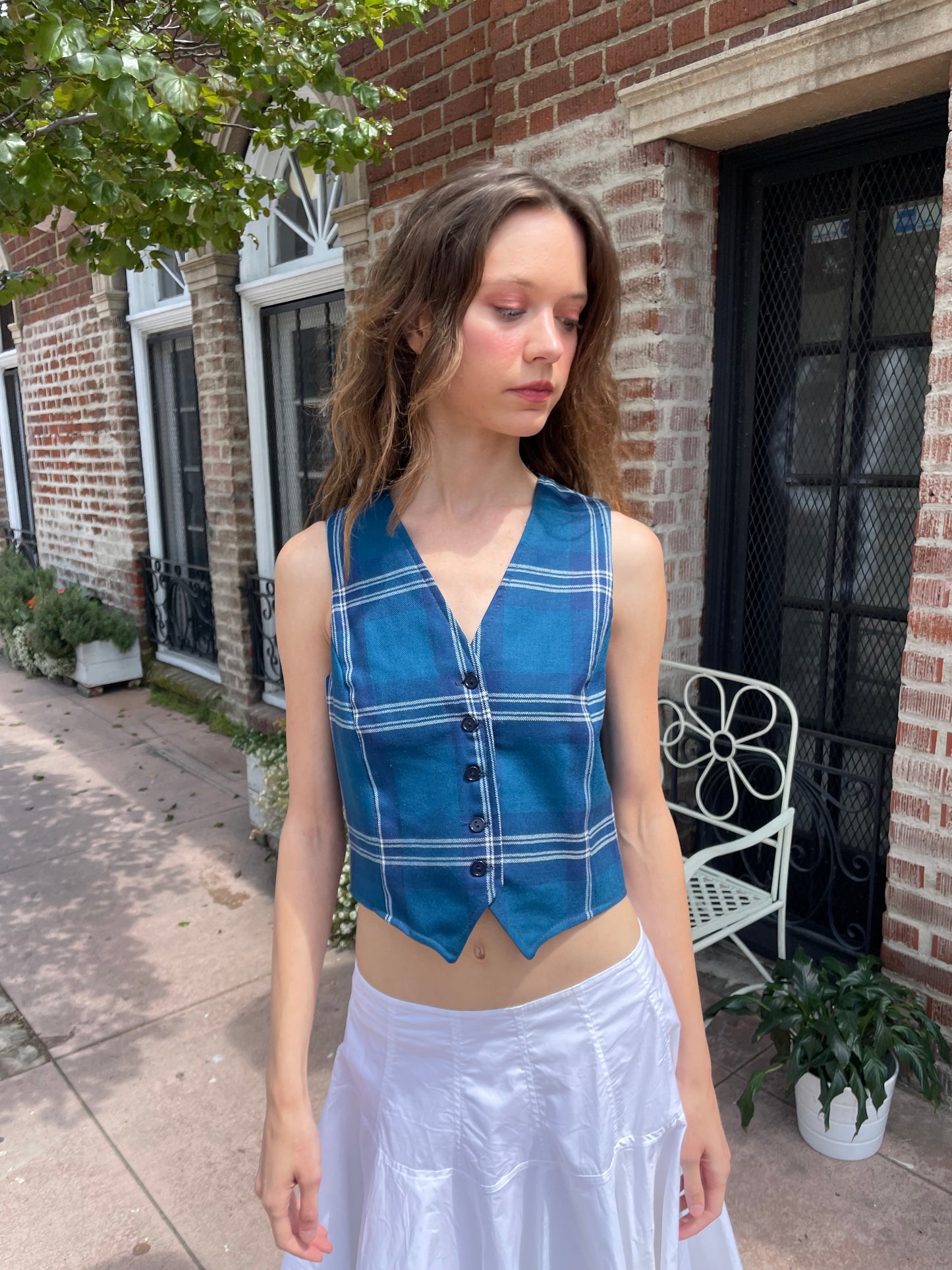 girl wearing blue plaid vest, white skirt and black boots