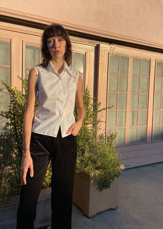 girl wearing sleaveless white button up and black pants