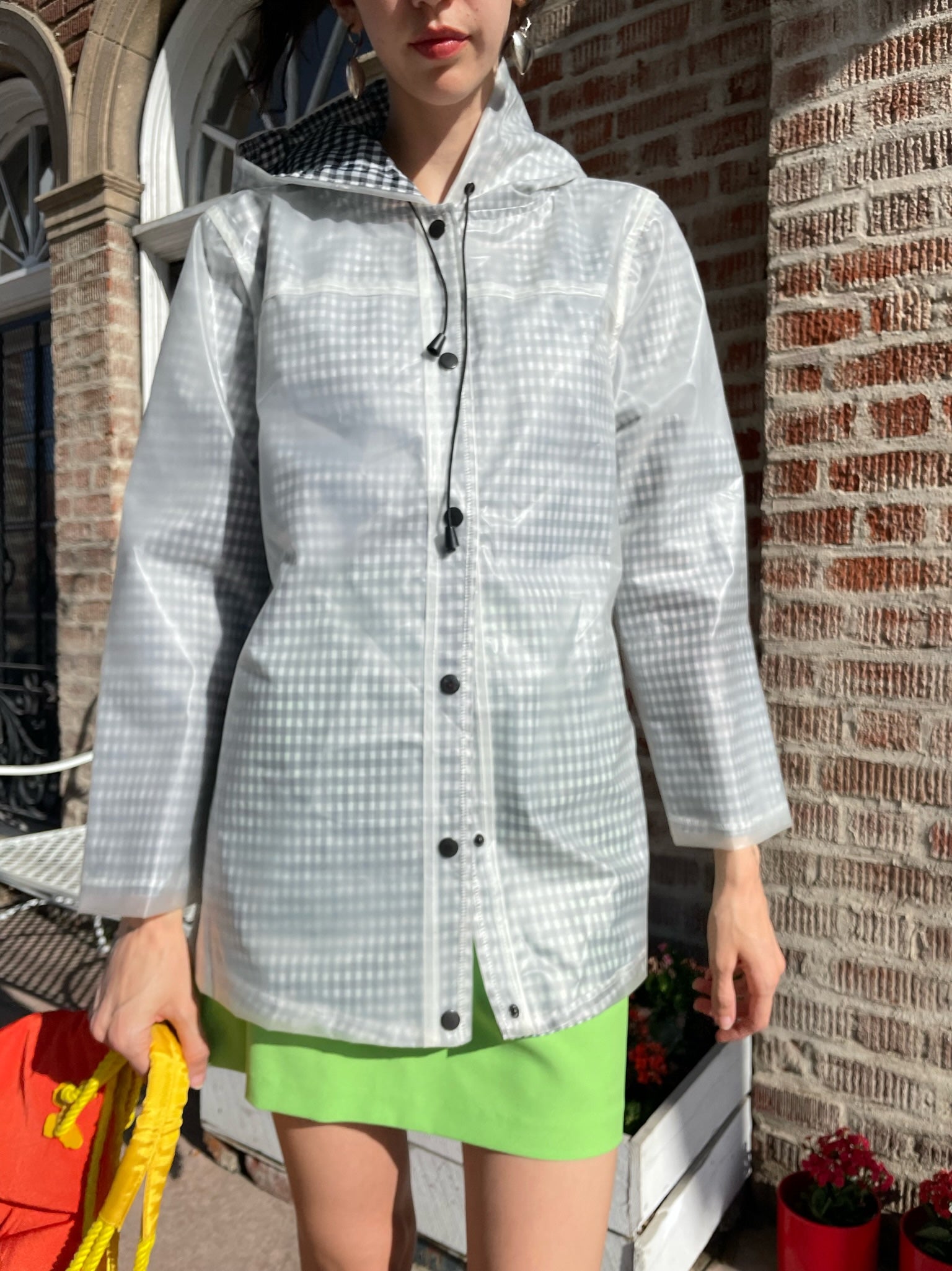 girl wearing gingham rain jacket, rhinestone tank top and bright green skirt
