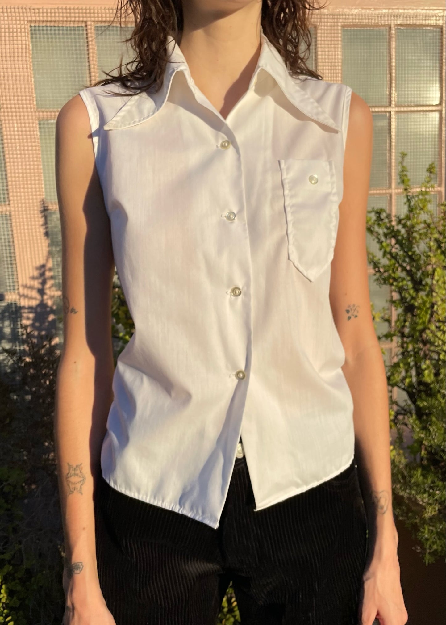 girl wearing sleaveless white button up and black pants
