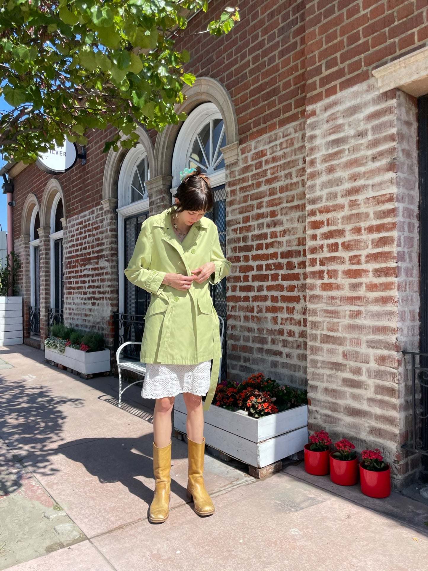 girl wearing light green pea coat and white skirt