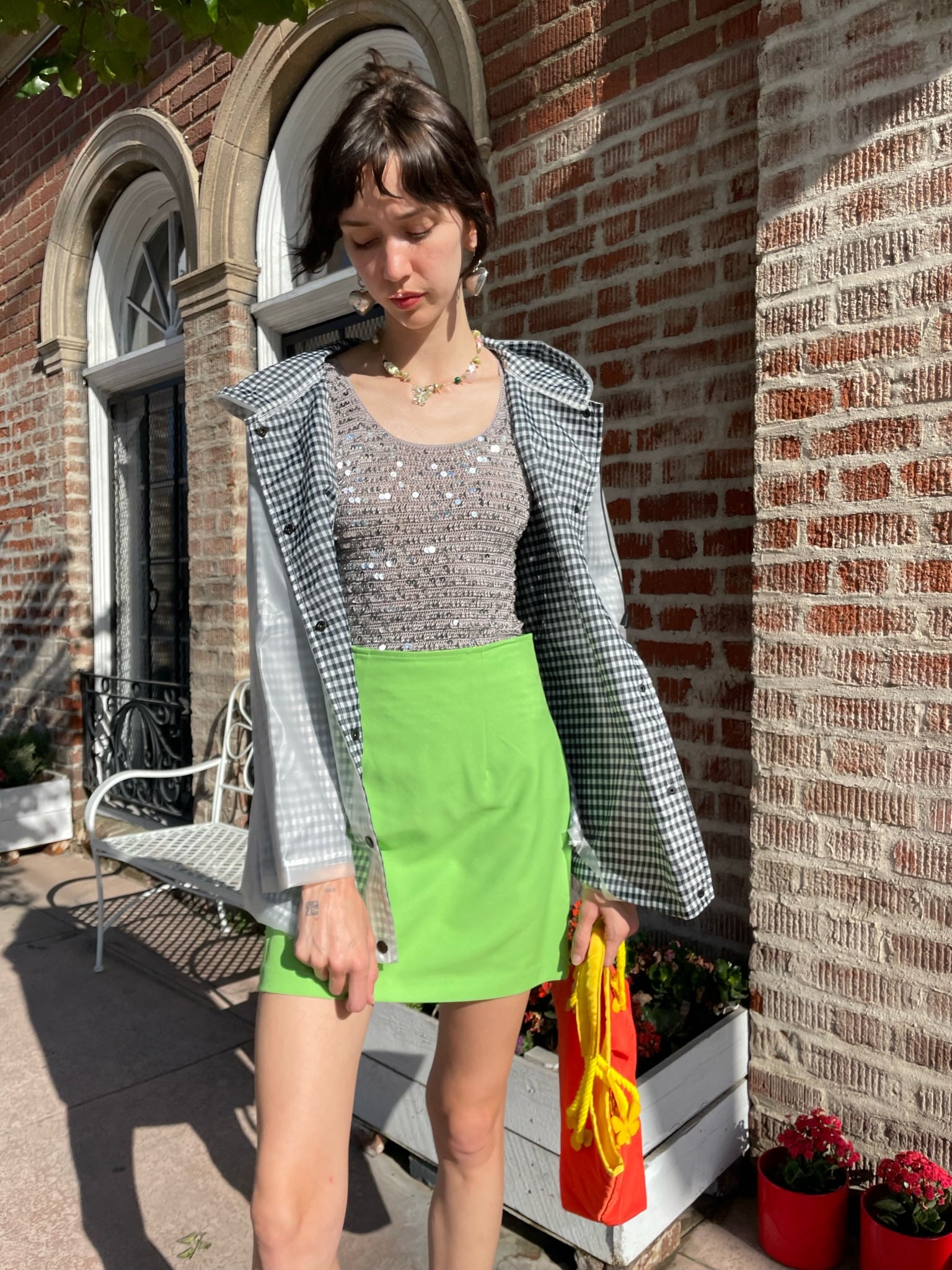 girl wearing gingham rain jacket, rhinestone tank top and bright green skirt