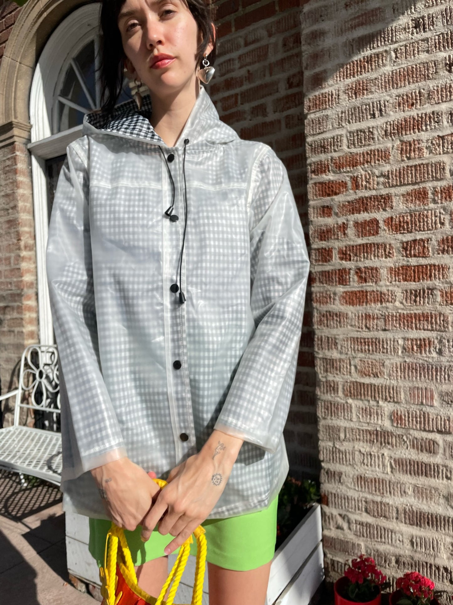 girl wearing gingham rain jacket, rhinestone tank top and bright green skirt
