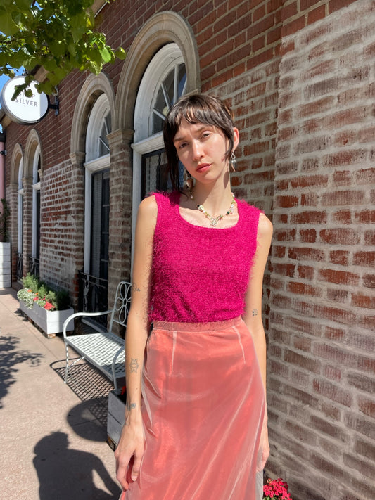 girl wearing a textured pink sleeveless top and red skirt with sheer white overlay