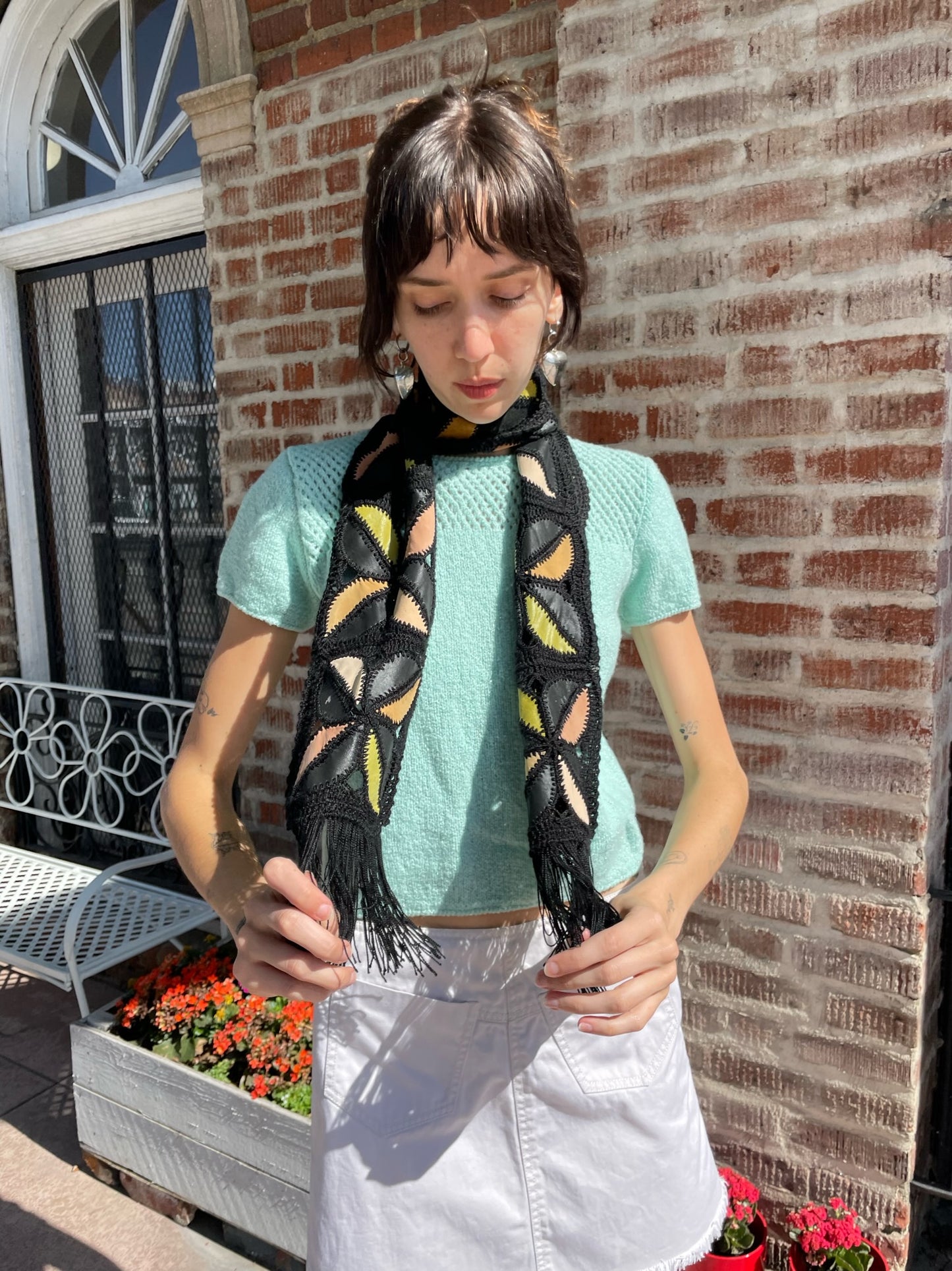 girl wearing blue top, white denim skirt and black scarf