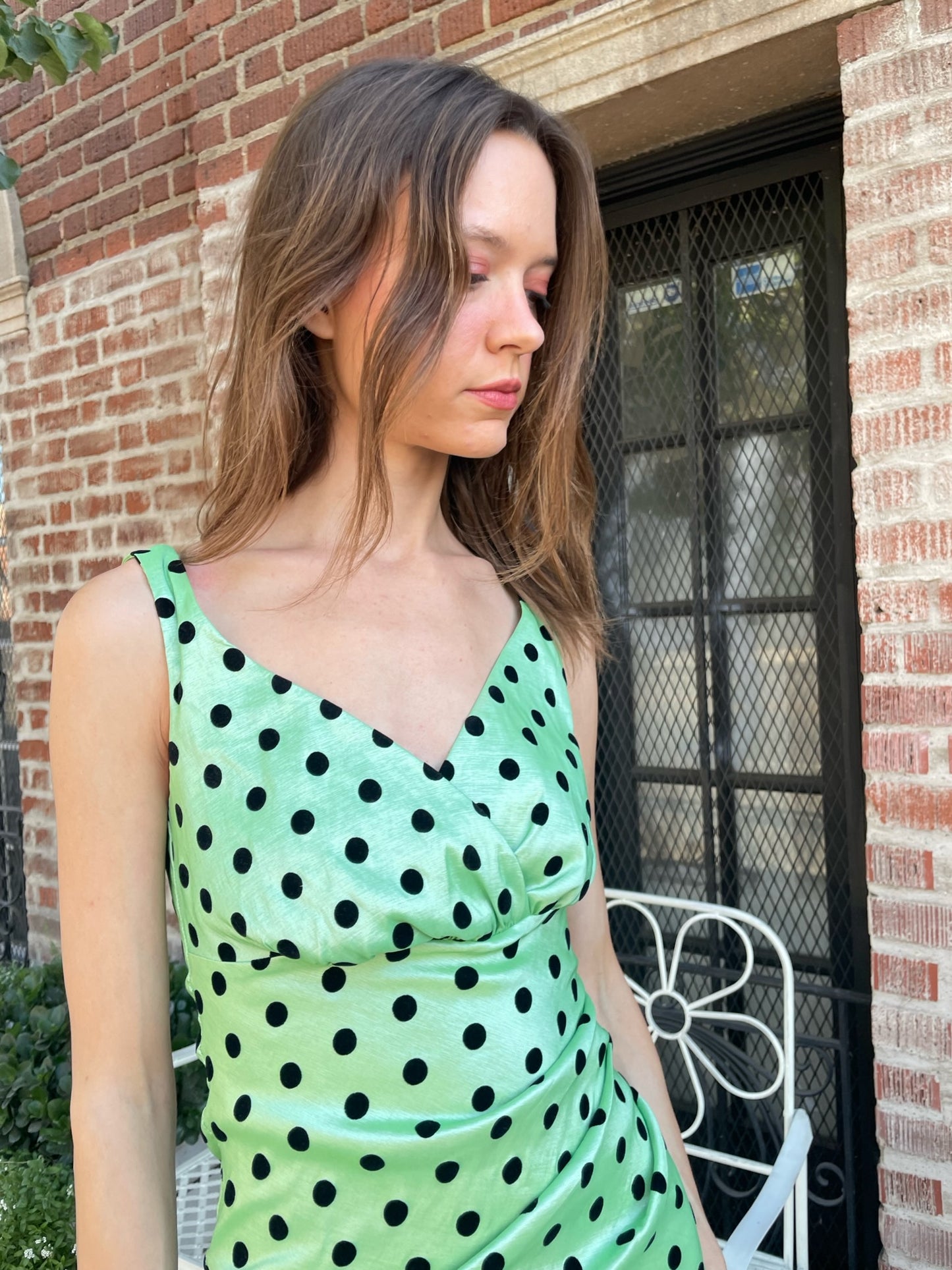 girl wearing a shiny green dress with black polka dots