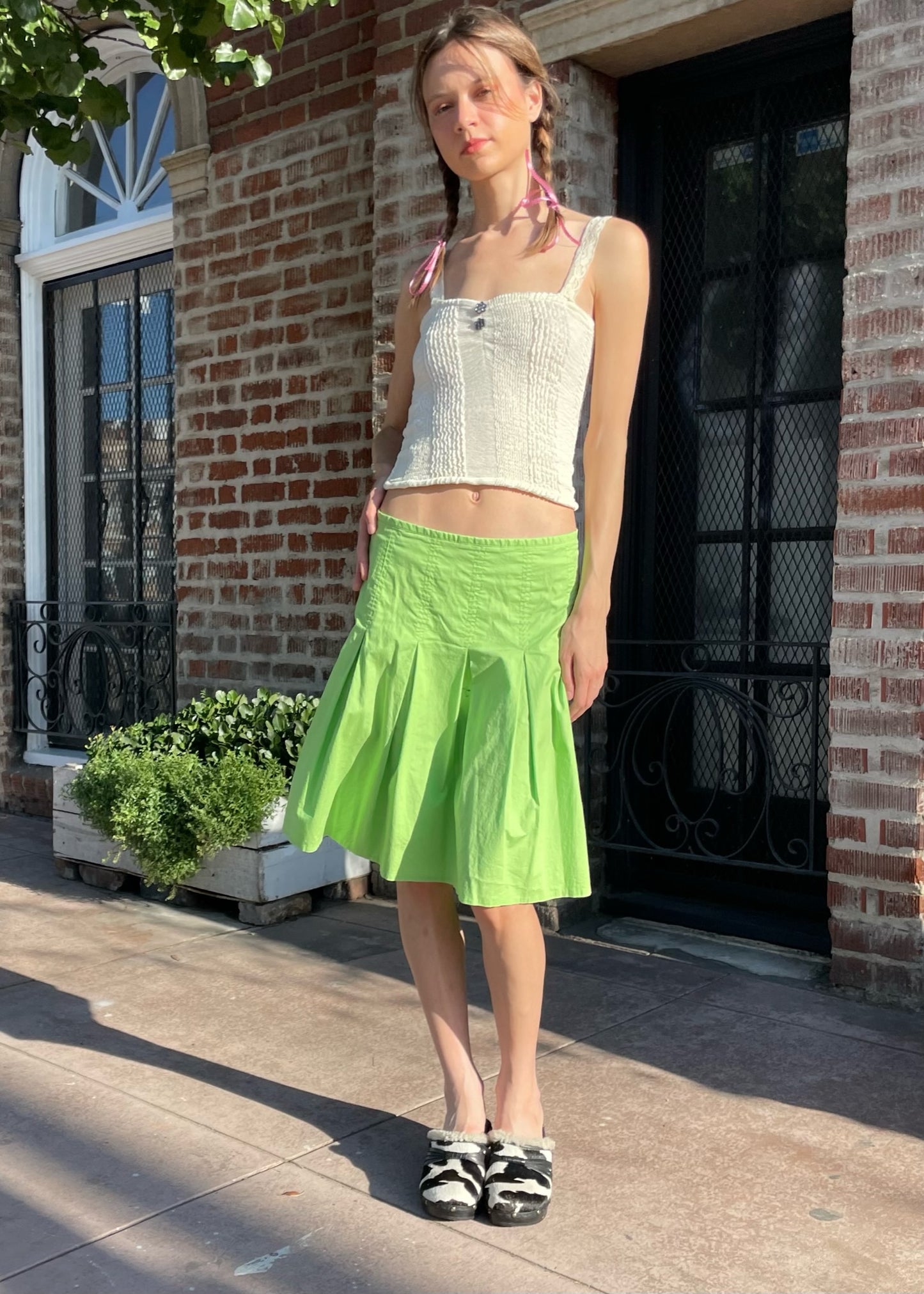 girl wearing a tan top and green skirt