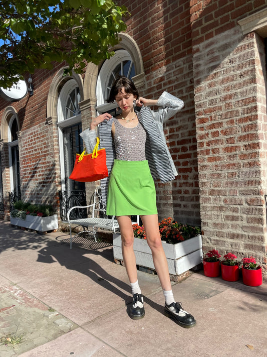 girl wearing gingham rain jacket, rhinestone tank top and bright green skirt