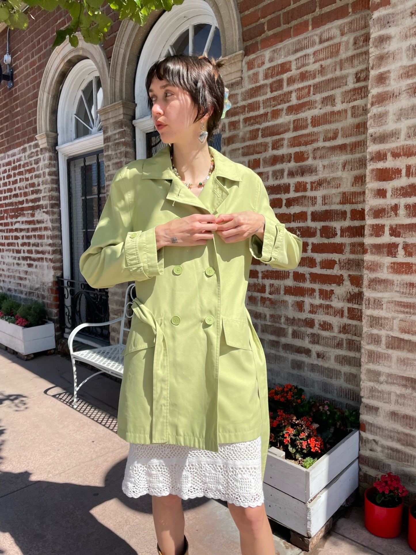 girl wearing light green pea coat and white skirt