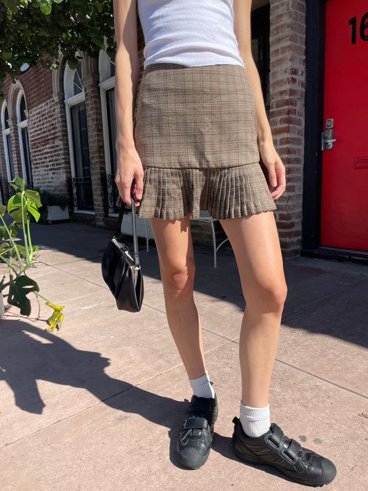 girl in white tank top and brown plaid skirt