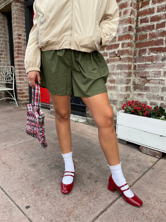 girl in green shorts and tan jacket