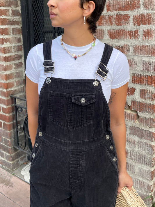 girl in black overalls and white t-shirt