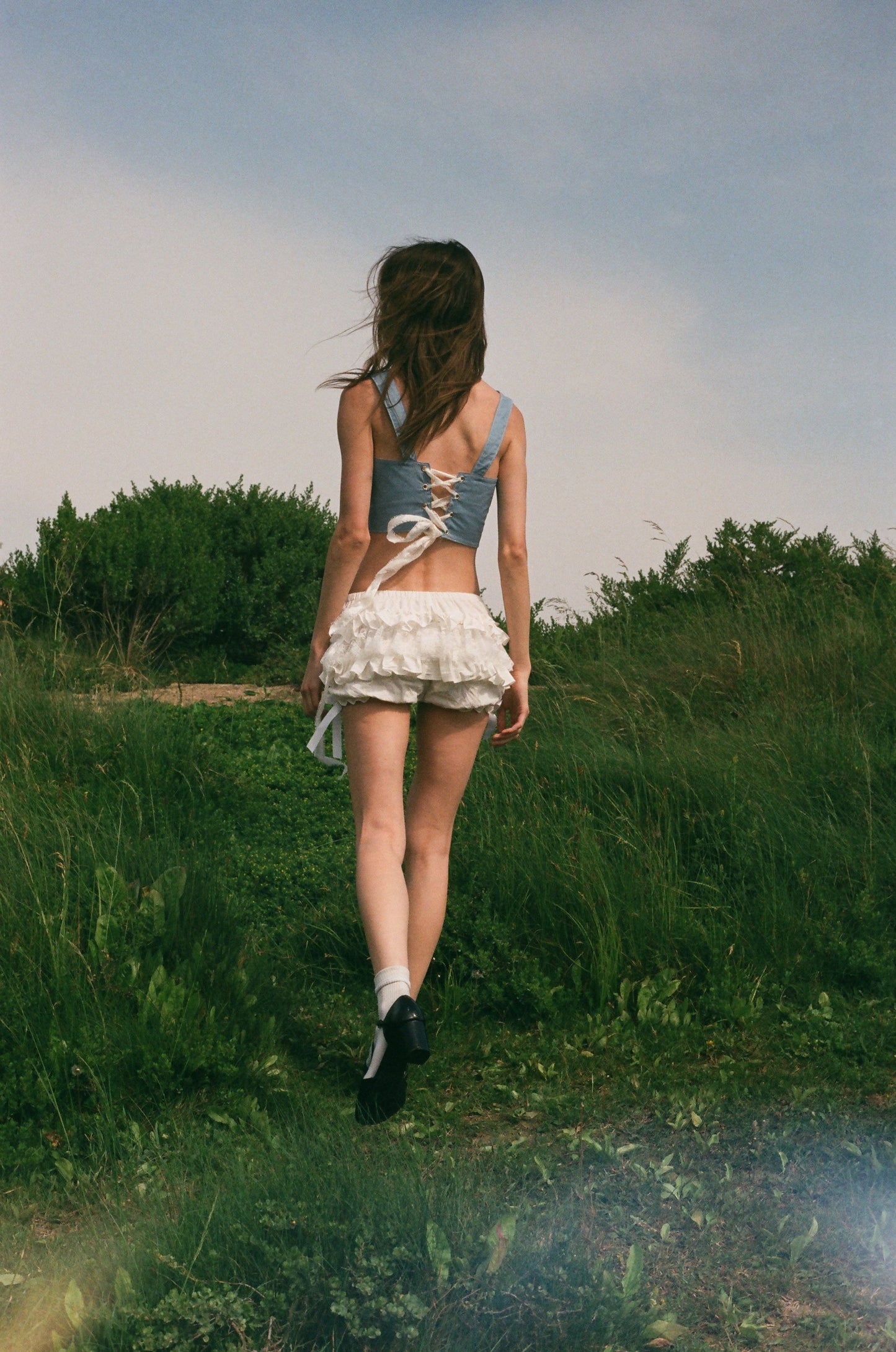 back of girl wearing a blue corset and white bloomers