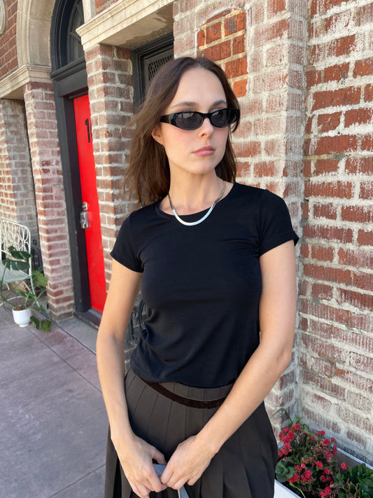 girl in cropped black top and brown skirt