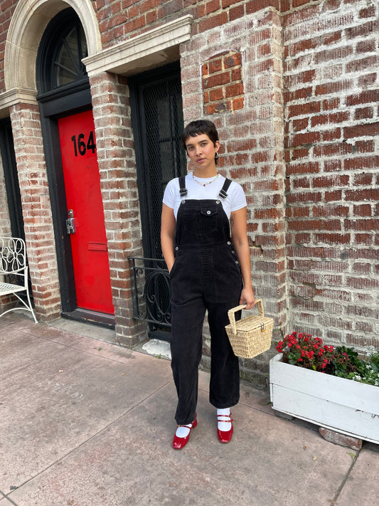 girl in black overalls and white t-shirt