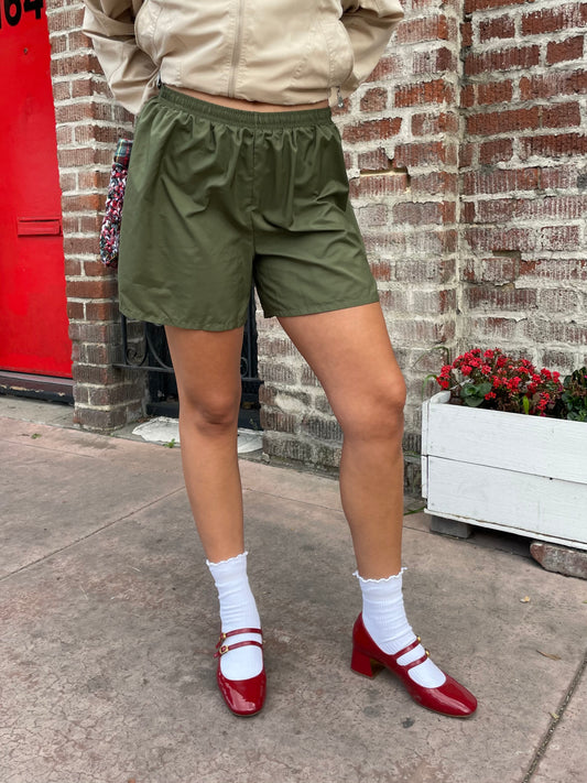 girl in green shorts and tan jacket