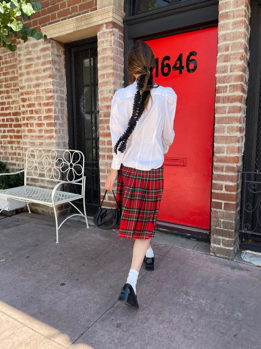 girl in white button up and plaid red skirt