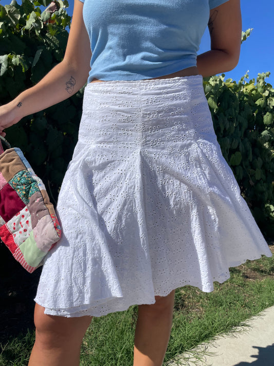 girl wearing white skirt blue top and adidas shoes