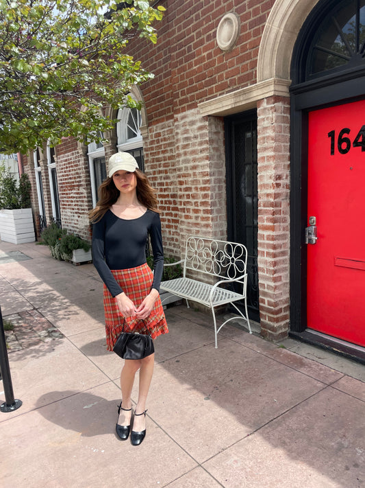 girl wearing long sleeve black shirt and red plaid skirt