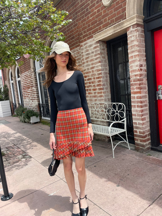 girl wearing long sleeve black shirt and red plaid skirt