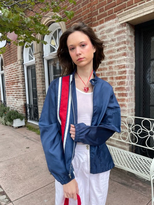 girl wearing blue jacket with red stripe, white tank top and white pants