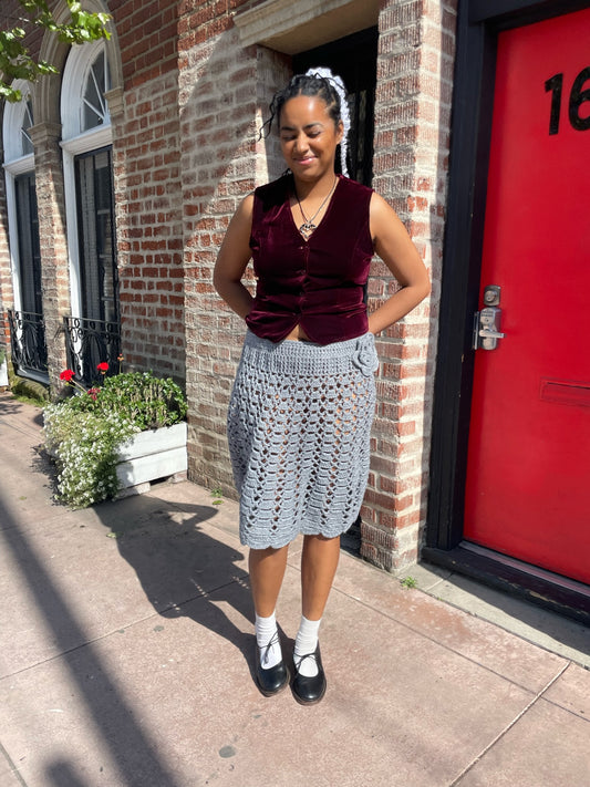 girl wearing a red velvet vest and light blue crochet skirt