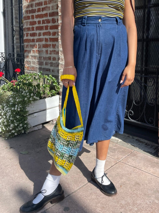 girl wearing long blue jean skirt and crochet purse