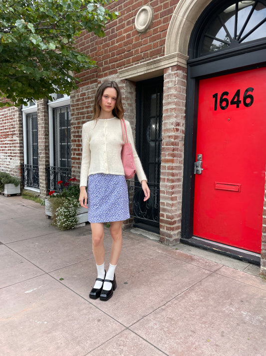 girl in cream cardigan and purple skirt