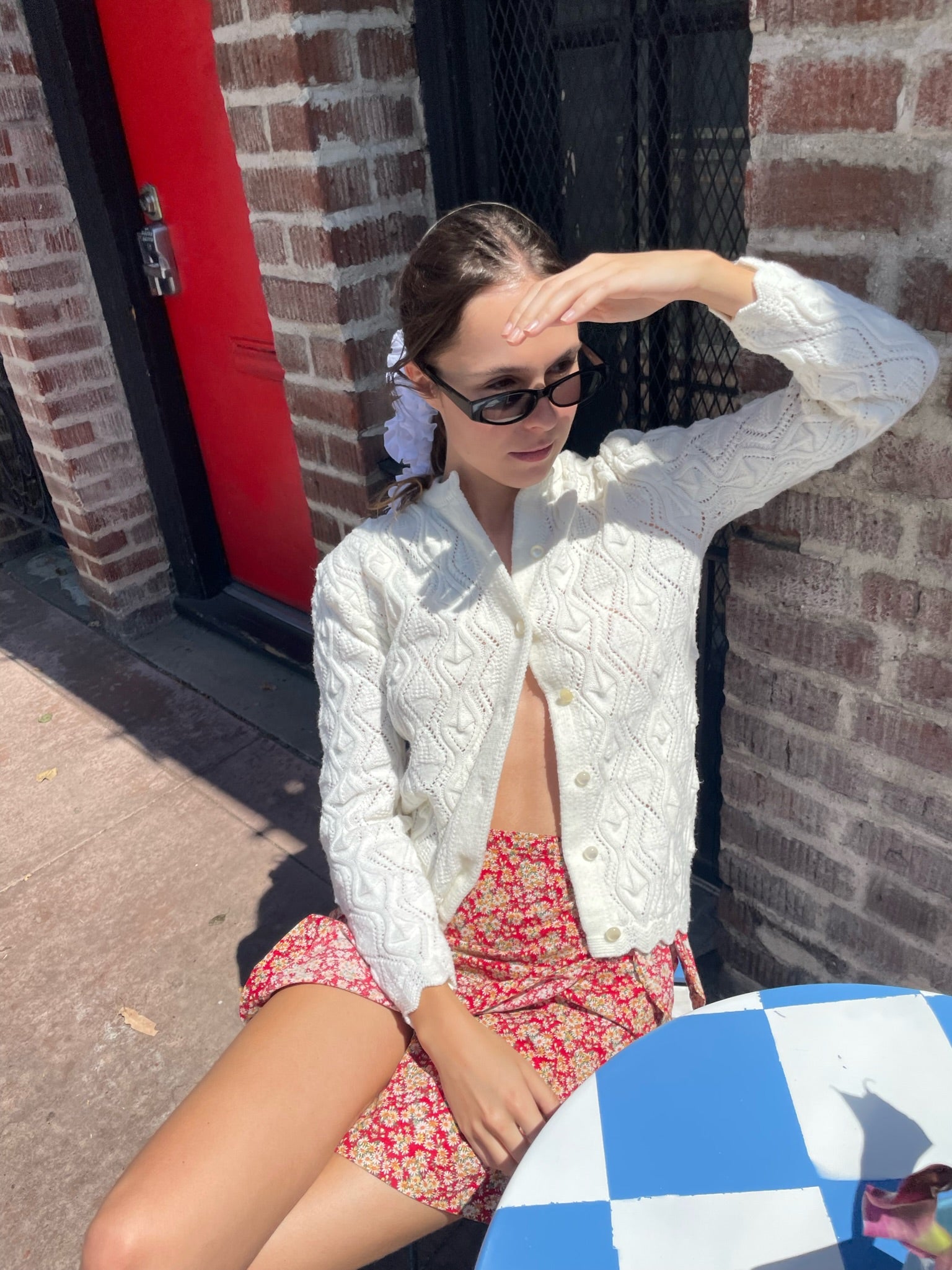 girl wearing red floral skirt and white cardigan