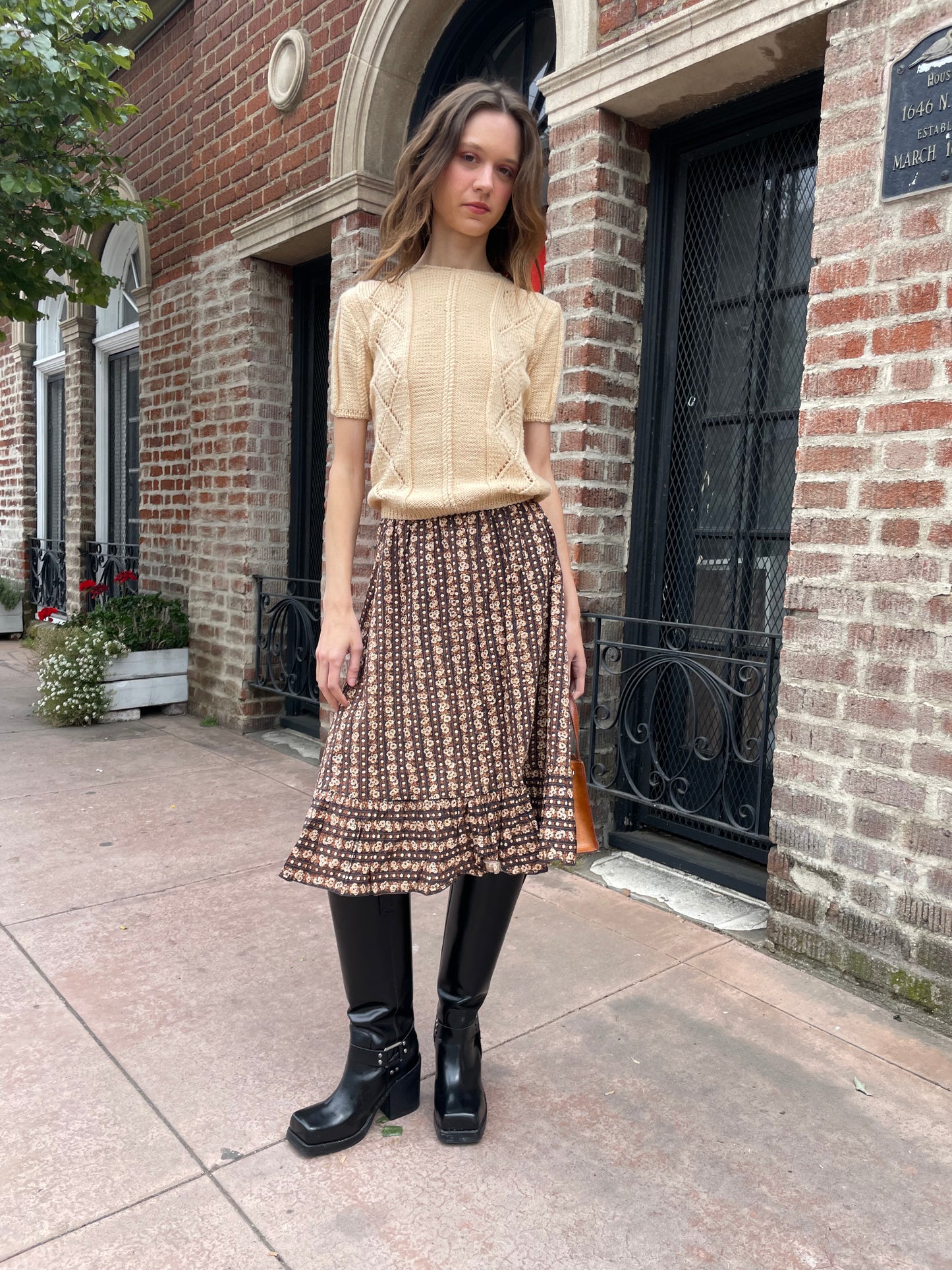 girl wearing cream sweater and brown floral skirt