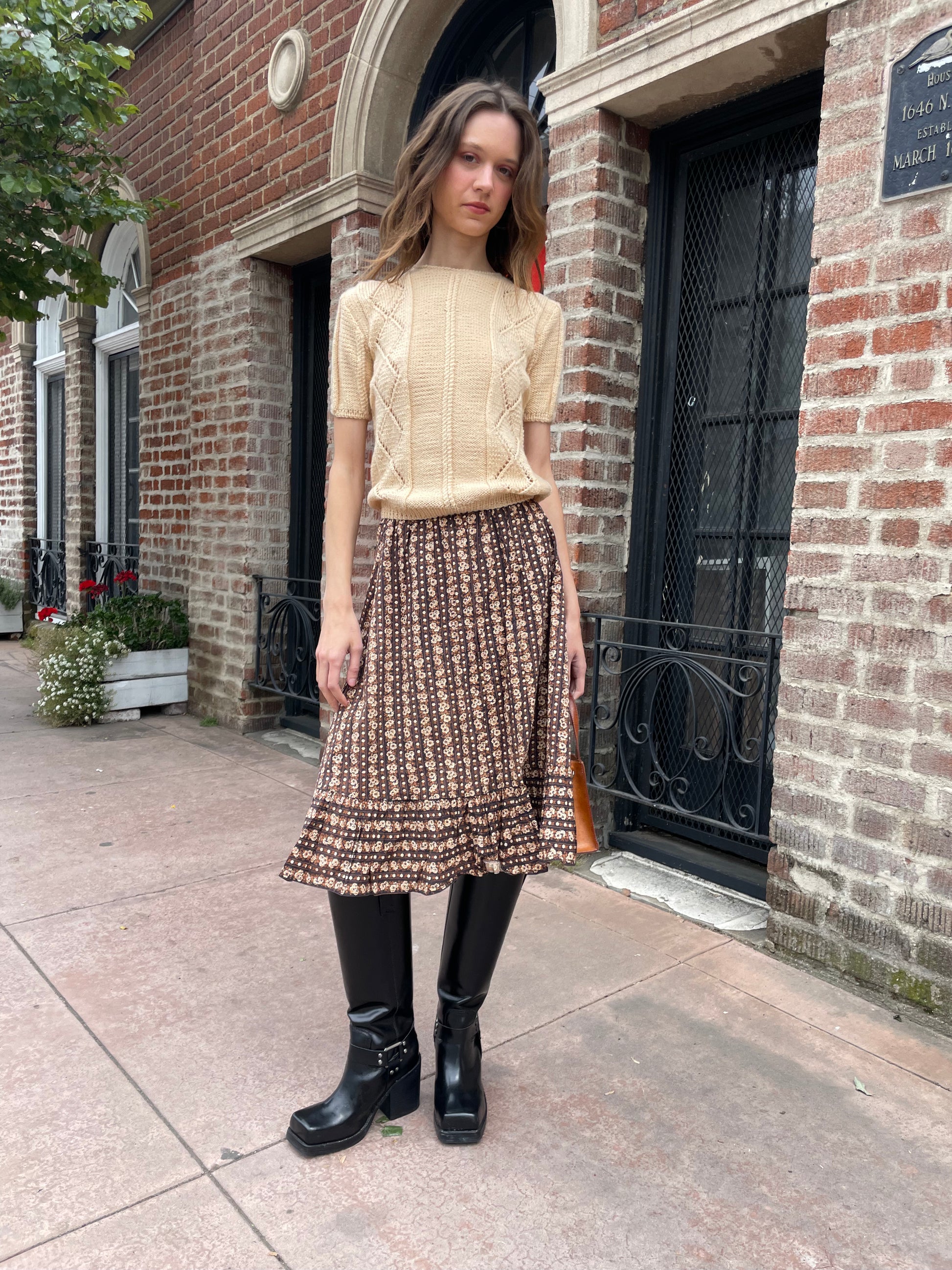 girl wearing cream sweater and brown floral skirt